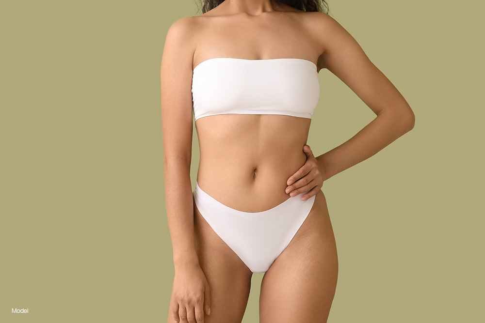 Curvy woman in white underwear against a green background